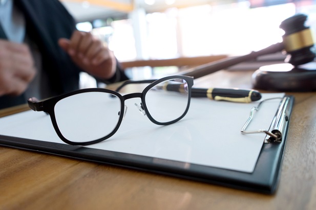 Stock photo: pair of glasses resting on legal pad and man's hand in background