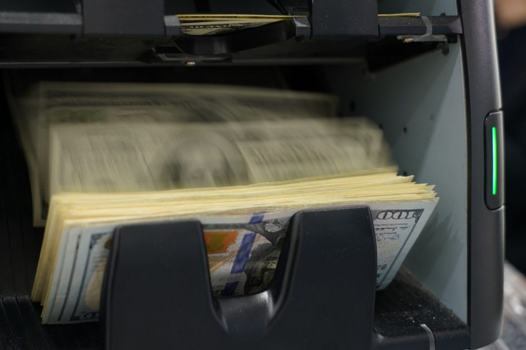 Photo: $100 bills being counted by a machine. Photographer: Toru Hanai/Bloomberg