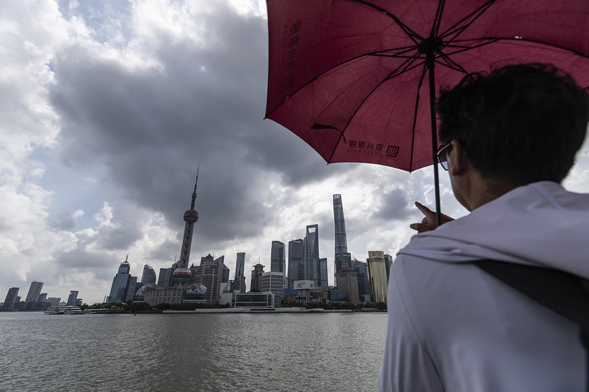 Photo: A pedestrian along the Bund across from commercial buildings in Pudong's Lujiazui Financial District in Shanghai, China, on August 14, 2024. Photographer: Qilai Shen/Bloomberg.