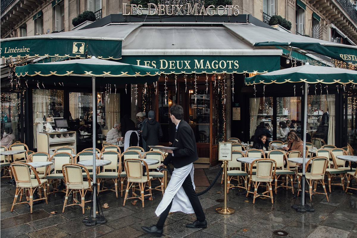 Photo: A waiter passes in front of the famous "Les deux Magots" cafe in Paris on January 2, 2023. Photographer: Cyril Marcilhacy/Bloomberg