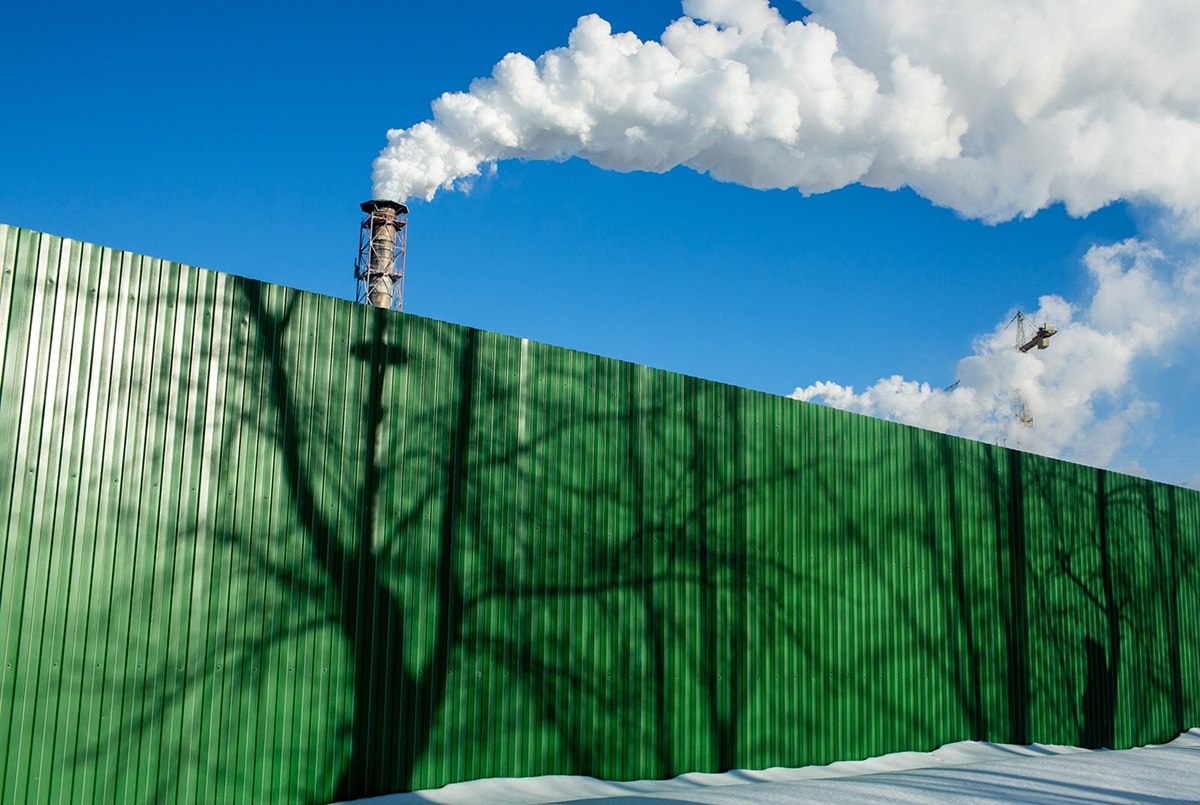 Photo: Chimneys emit vapor behind a perimeter fence with tree shadows at the Segezha Pulp and Paper Mill JSC, operated by Segezha Group, in Segezha, Russia, on Friday, March 19, 2021. 