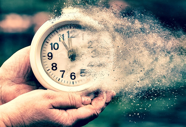 woman's hands holding a clock that is turning to dust