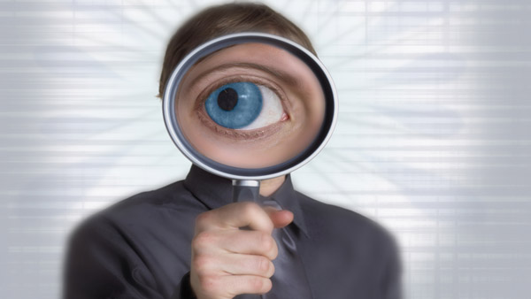 Businessman with magnifying glass in front of face